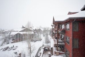 Una zona residencial cubierta de nieve, con edificios de varios pisos, un estacionamiento y una carretera visible.