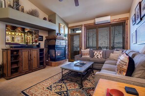 A cozy living room with a fireplace, a sofa, a coffee table, and a TV. - CL3305 | Top Floor | Vaulted Ceilings | 10 Hot Tubs | Winter Shuttle | 4 Pools (Steamboat Springs)