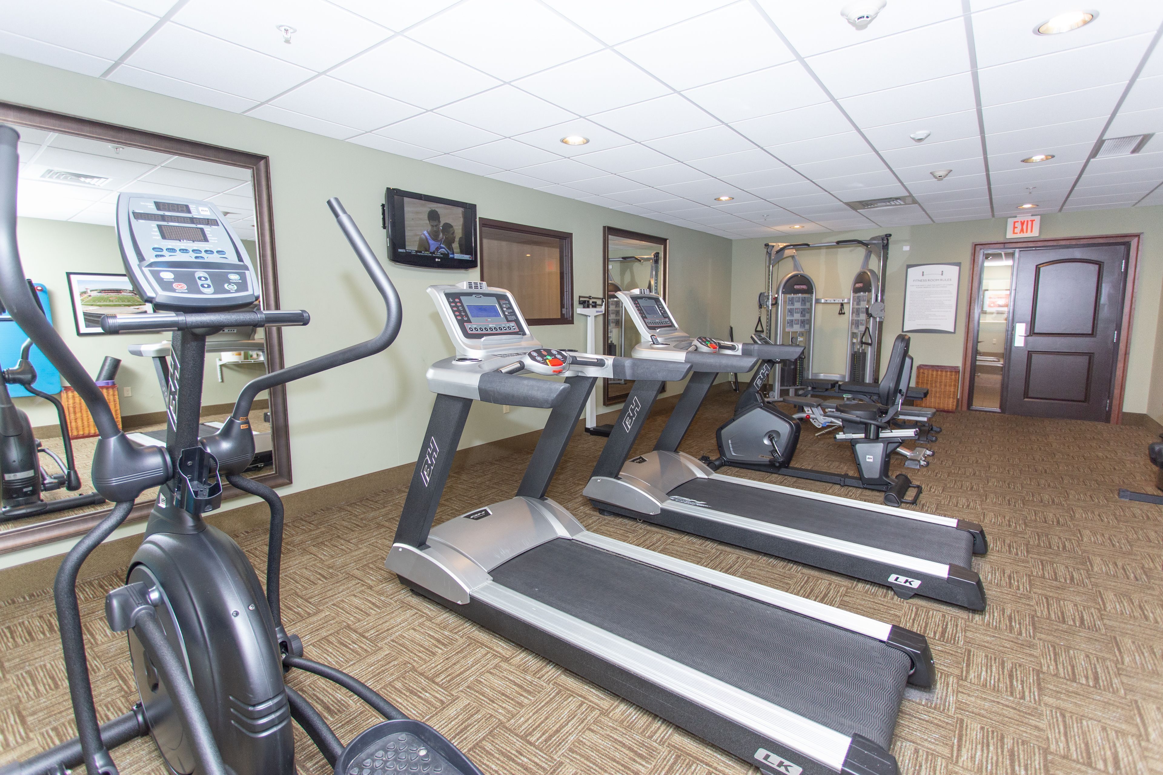 A gym with treadmills, elliptical machines, and exercise equipment.