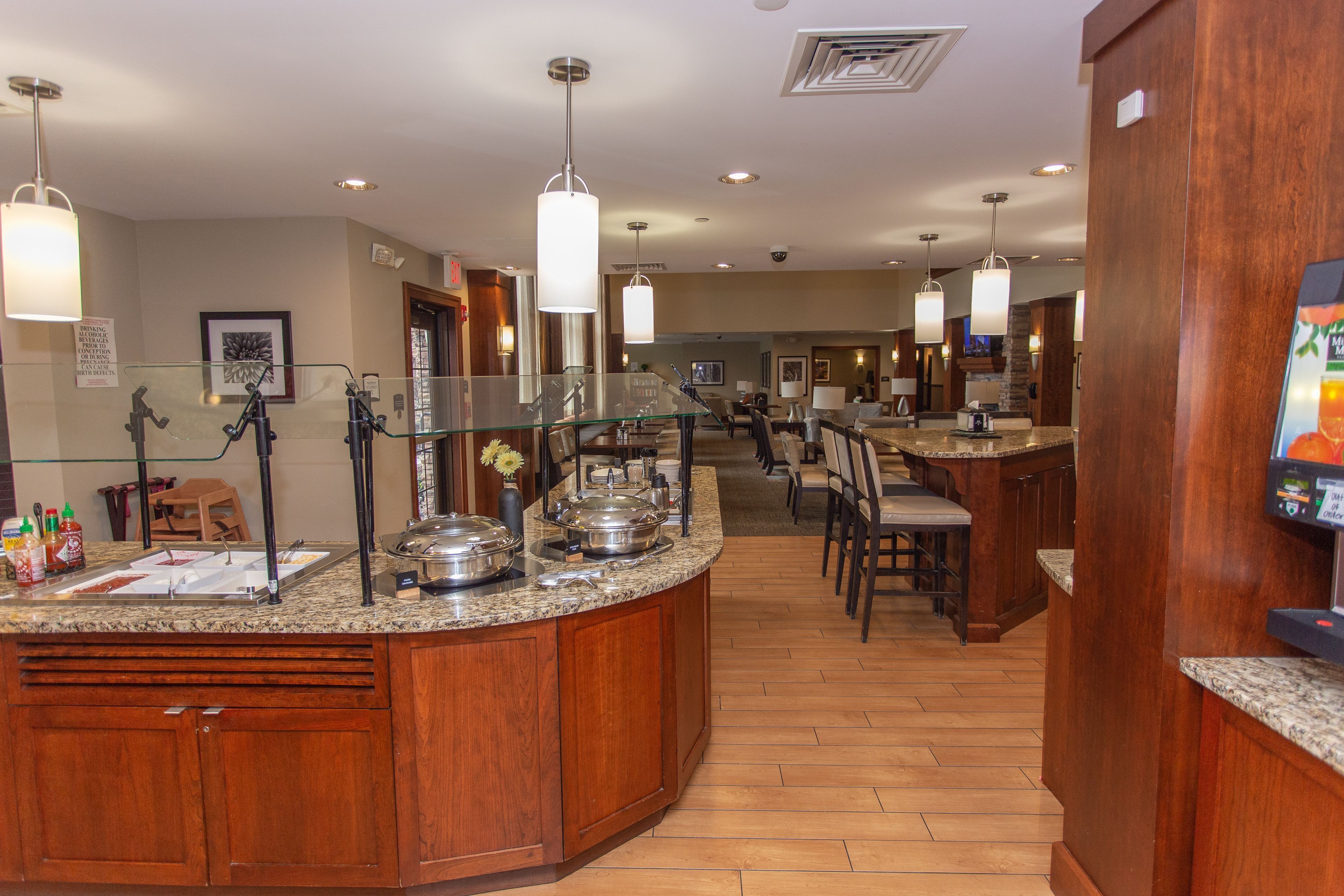 Una cocina de hotel con encimeras de granito, electrodomésticos de acero inoxidable y armarios de madera.