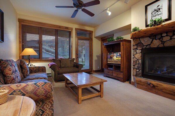 A living room with a fireplace, a television, a ceiling fan, and a couch. - TL2111 | Nice Ground Floor Condo | Winter Shuttle | Close to Slopes | Hot Tubs (Steamboat Springs)