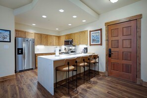 A kitchen with wooden cabinets, a stainless steel refrigerator, a microwave, and a wooden door. - CL3209 | Newly Listed | Close to Skiing | Perfect for Couples | A/C (Steamboat Springs)