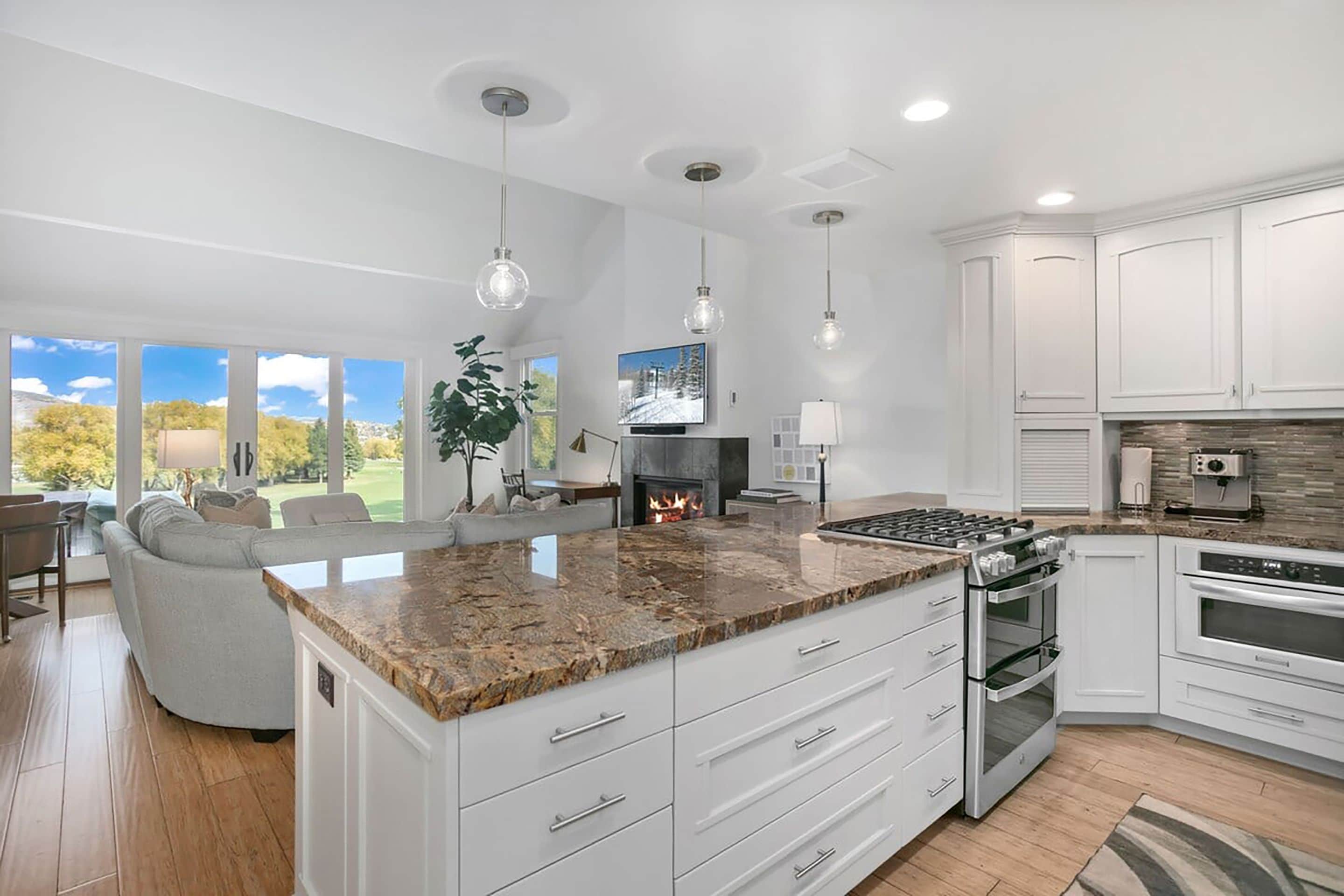 A modern kitchen with white cabinetry, a granite countertop, and stainless steel appliances.