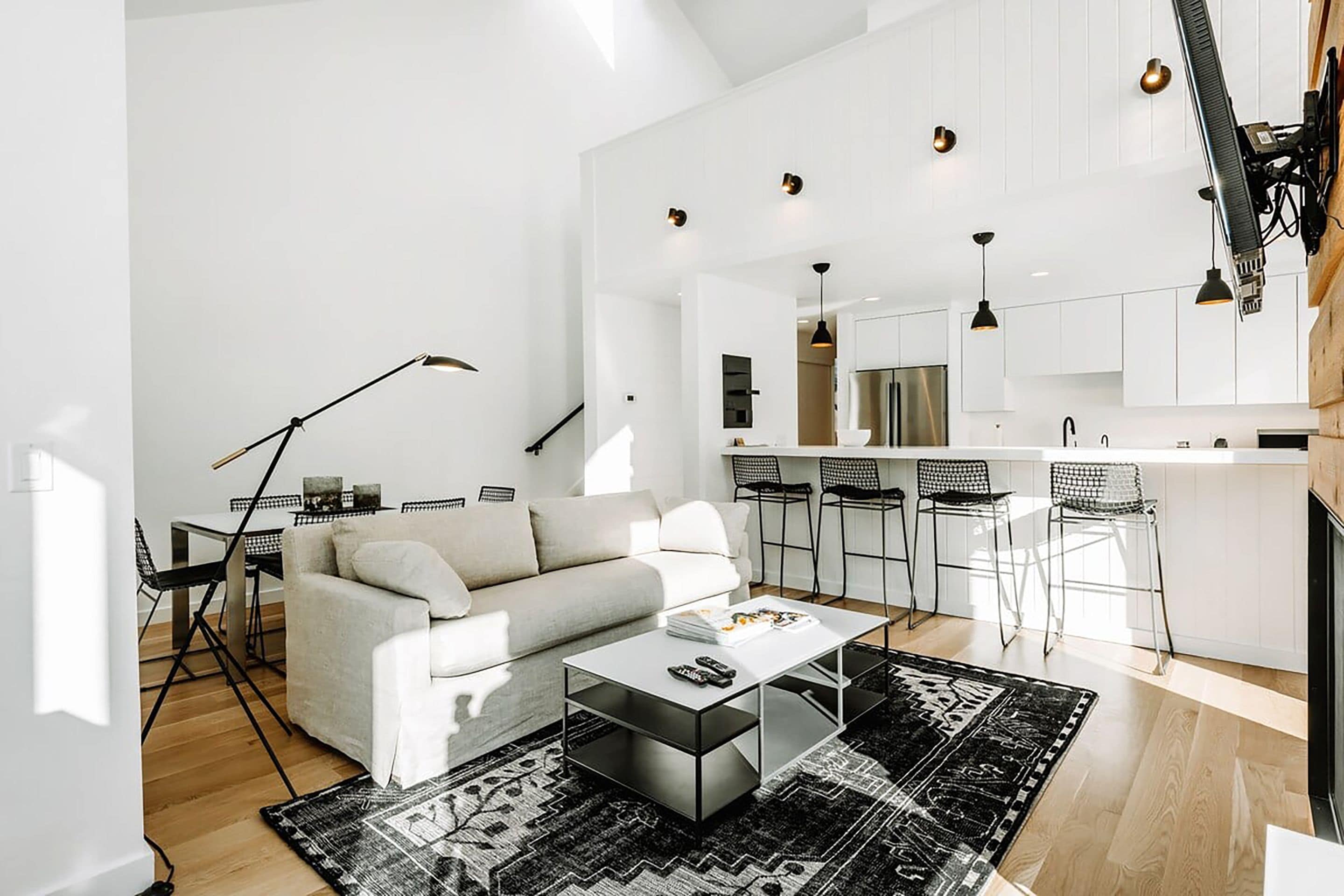 Una sala moderna con un sofá, una mesa de centro y una zona de comedor con sillas.