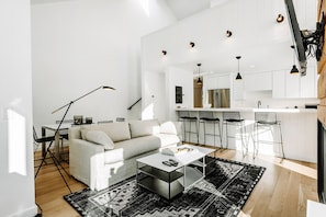 Una sala moderna con un sofá, una mesa de centro y una zona de comedor con sillas.