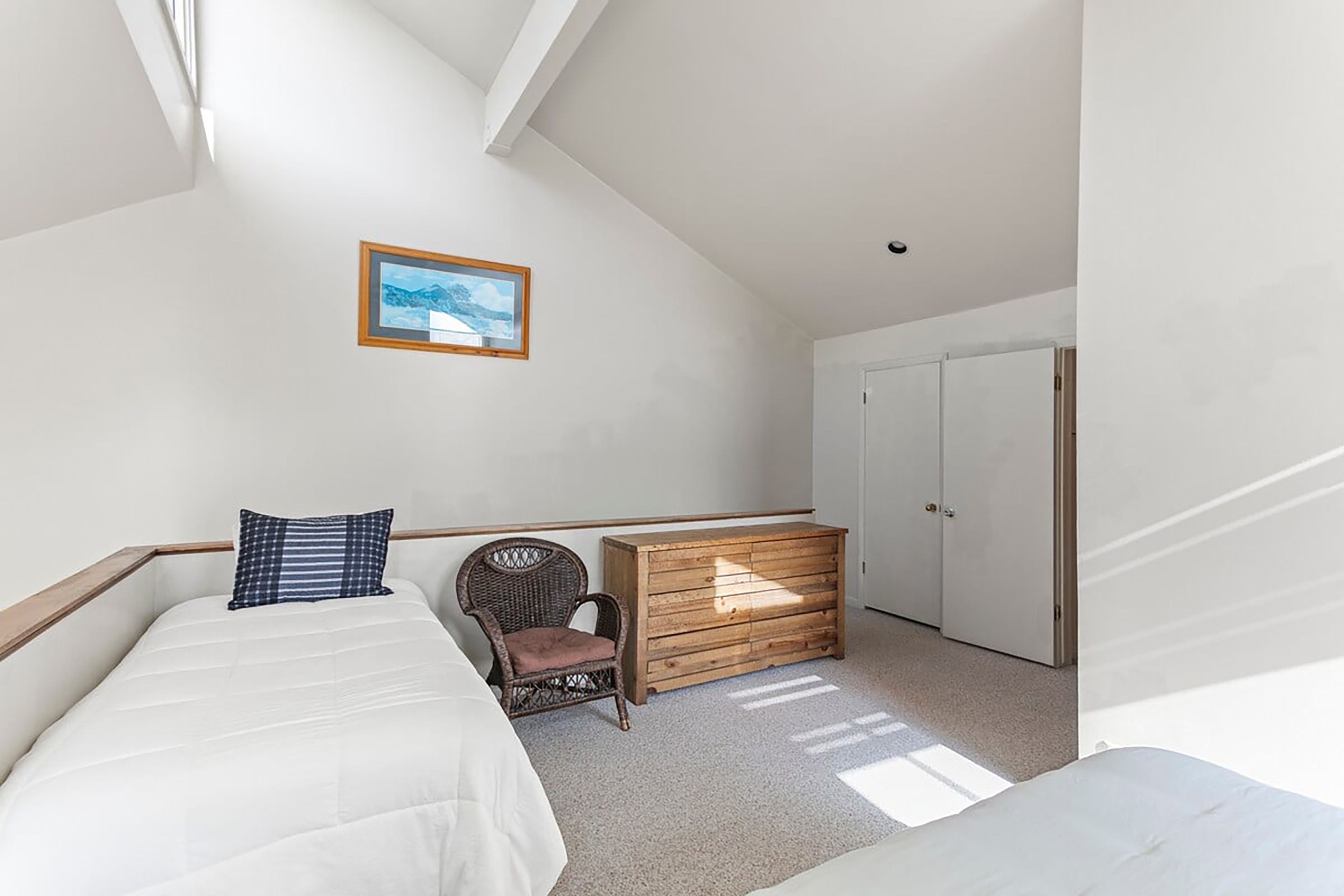 A bedroom with a bed, a chair, a dresser, and a wardrobe.