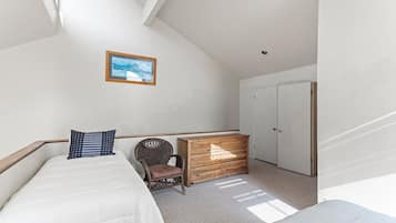 A bedroom with a bed, a chair, a dresser, and a wardrobe.