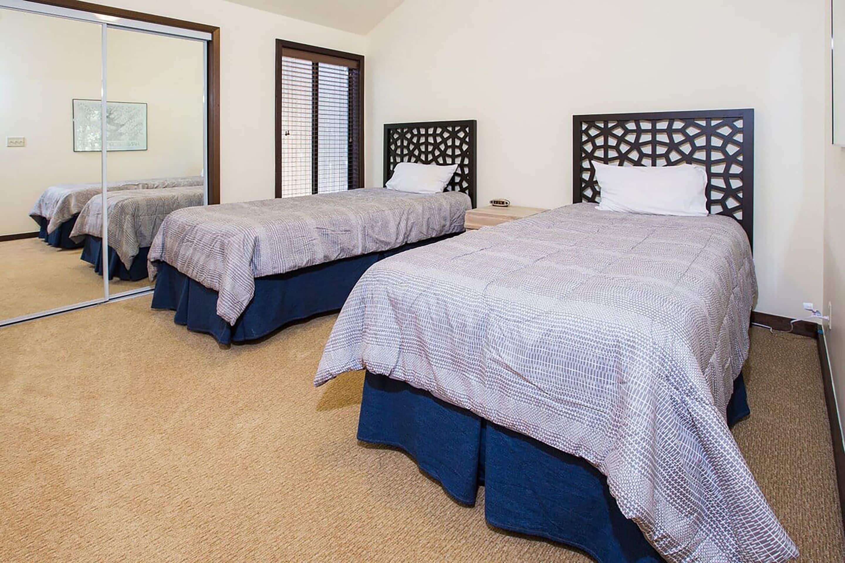 A hotel room with three beds, each with a patterned bedspread and matching headboard.