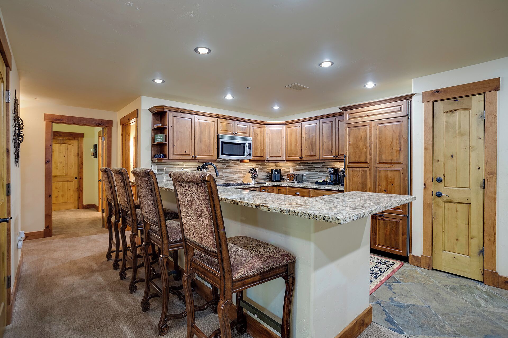 A kitchen with wooden cabinets, a granite countertop, and a built-in microwave.