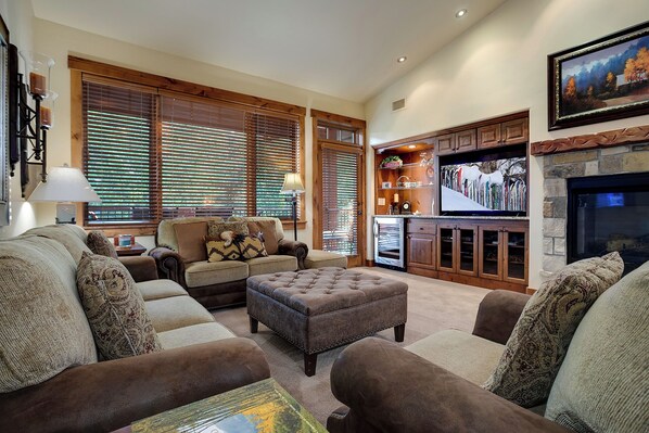A cozy living room with a fireplace, a television, and a kitchen area with wooden cabinets. - EL5308 | Beautifully Designed | Comfort | Convenience | Air Chilling | Hot Tub (Steamboat Springs)