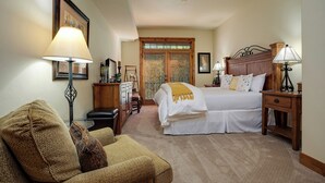 Quarto com cama, mesas de cabeceira, uma cadeira e escrivaninha.