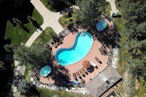 Aerial view showcasing the property's sprawling outdoor area with an inviting kidney-shaped pool, jacuzzi, and ample deck space surrounded by lush greenery and shade trees. - EL5107 | Private Patio with Hot Tub | Air Chilling | Close to Skiing | 4 Pools (Steamboat Springs)