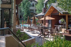 An outdoor patio area with tables and chairs, umbrellas, and a pool. - EL5107 | Private Patio with Hot Tub | Air Chilling | Close to Skiing | 4 Pools (Steamboat Springs)