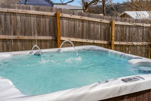 Ett bubbelbad med vattenstrålar, omgivet av ett trästaket.