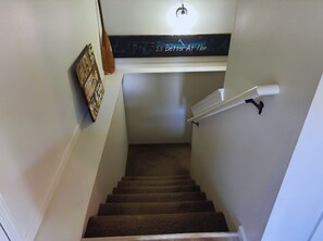 A carpeted staircase with a handrail, a wall-mounted light fixture, and a chalkboard with a motivational quote. - Downtown Branson 3BR Family-friendly Getaway (Branson)