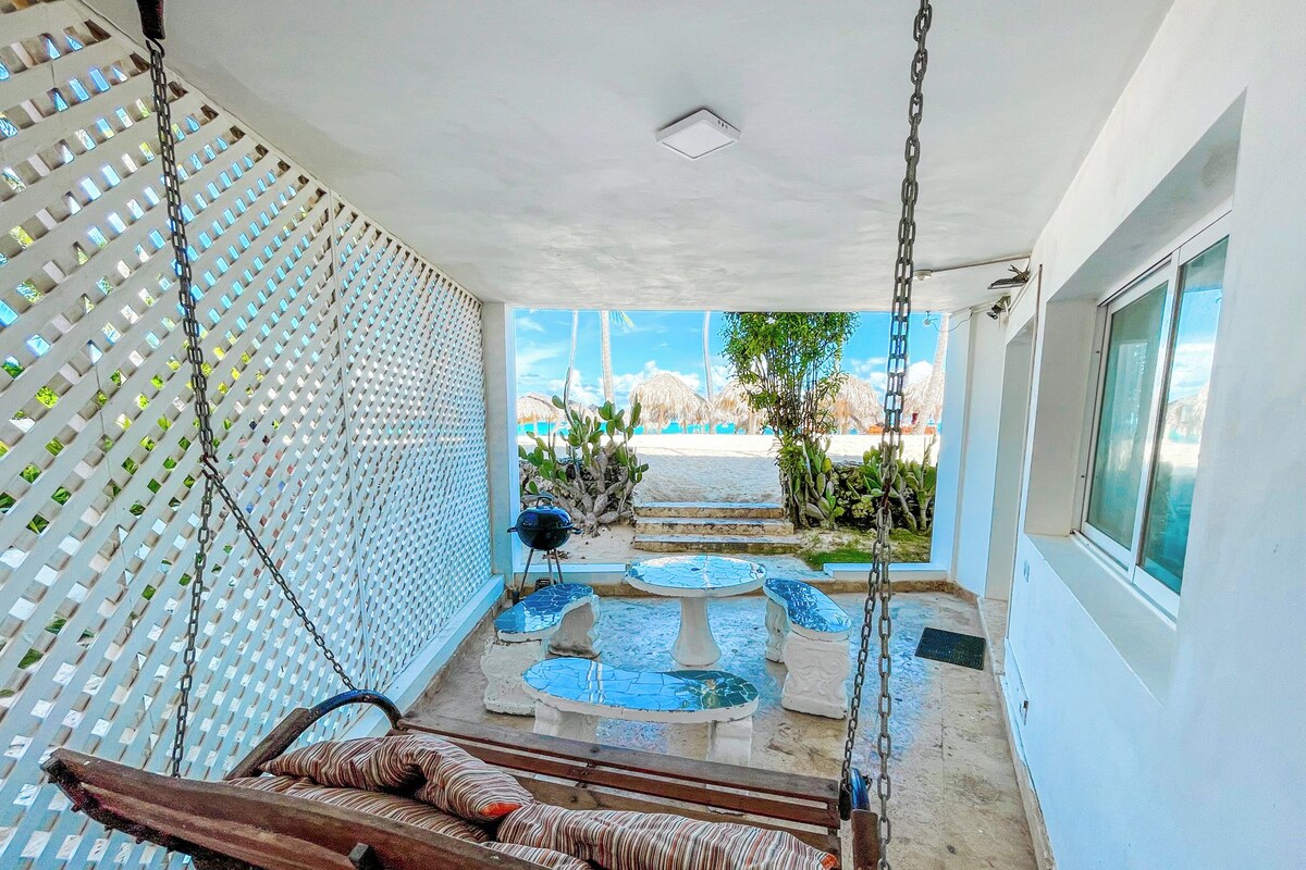 Quarto com balanço, uma pequena mesa e vista para a praia.
