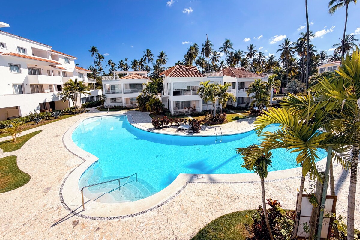 Um resort com piscina, palmeiras e edifícios altos.