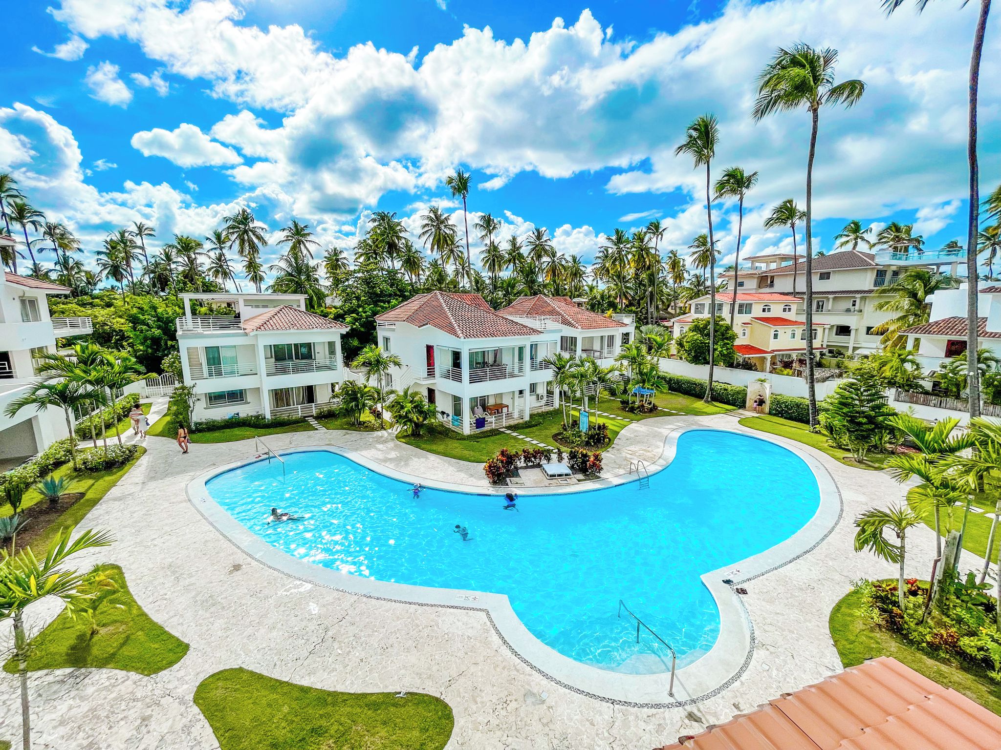 Um resort com uma piscina grande, edifícios de vários andares e palmeiras.