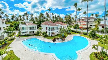 Um resort com uma piscina grande, edifícios de vários andares e palmeiras.