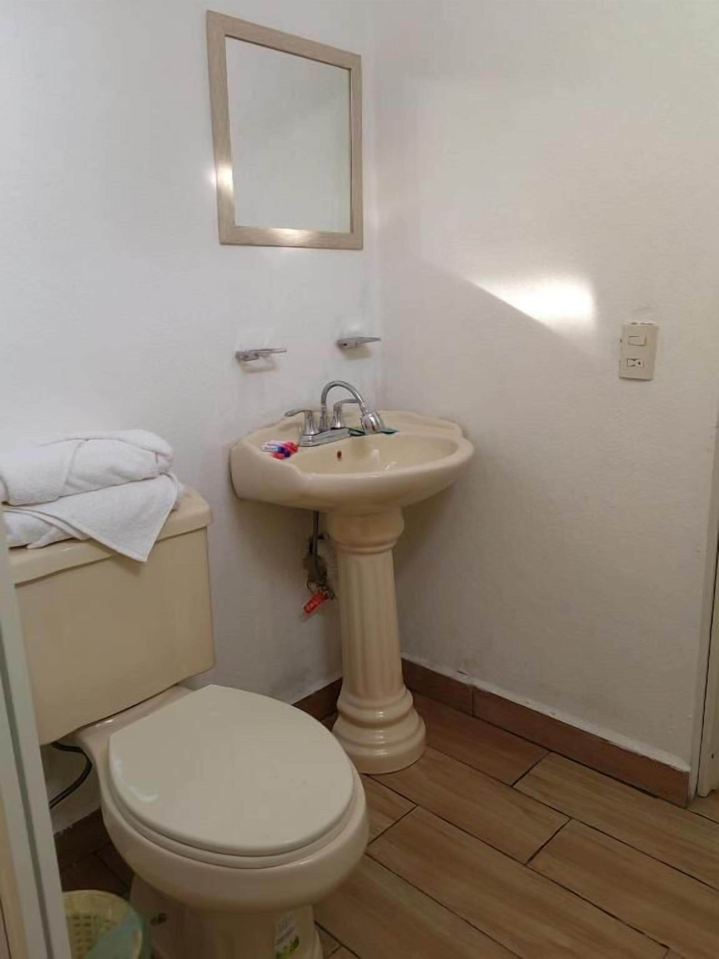 Un baño pequeño con inodoro, lavamanos y espejo.