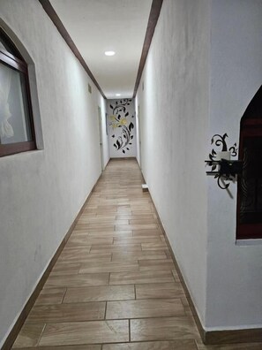 Un pasillo con piso de madera, paredes blancas y un adorno en la pared.
