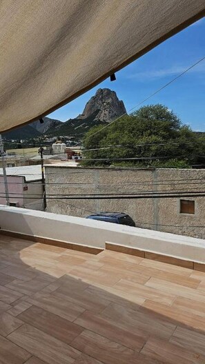 Un balcón con vista a una montaña y un edificio al fondo.