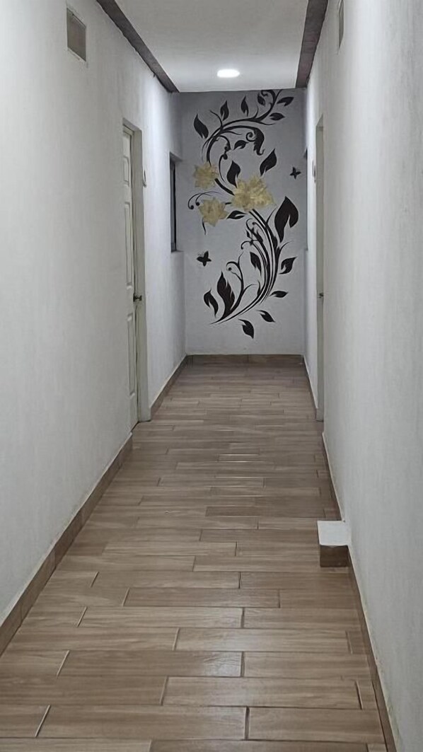 A narrow hallway with a wooden floor and a wall mural. - Posada villa aurora (Ezequiel Montes)