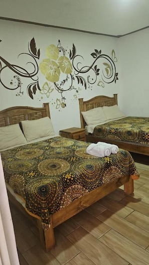 A room with two wooden beds, each with a patterned bedspread and matching pillows. - Posada villa aurora (Ezequiel Montes)