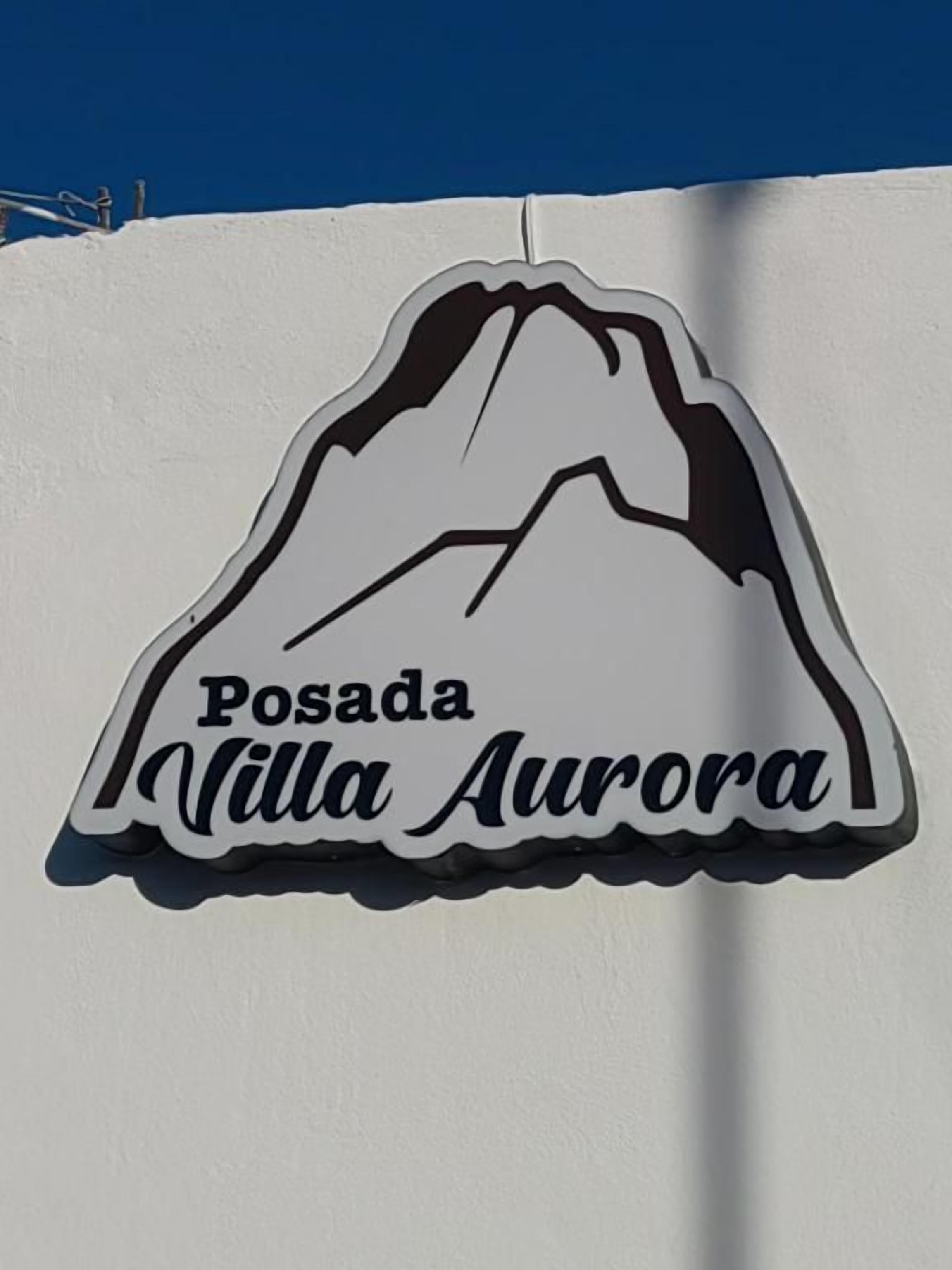 A sign with a mountain silhouette and the text 'Posada Villa Aurora'.