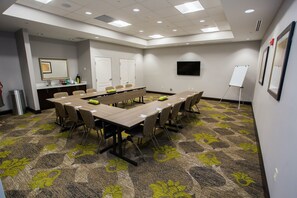 A conference room with a long table, chairs, a whiteboard, and a carpeted floor.