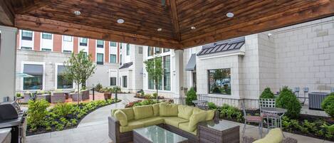 An outdoor patio area with wicker furniture, a ceiling fan, and a grill.