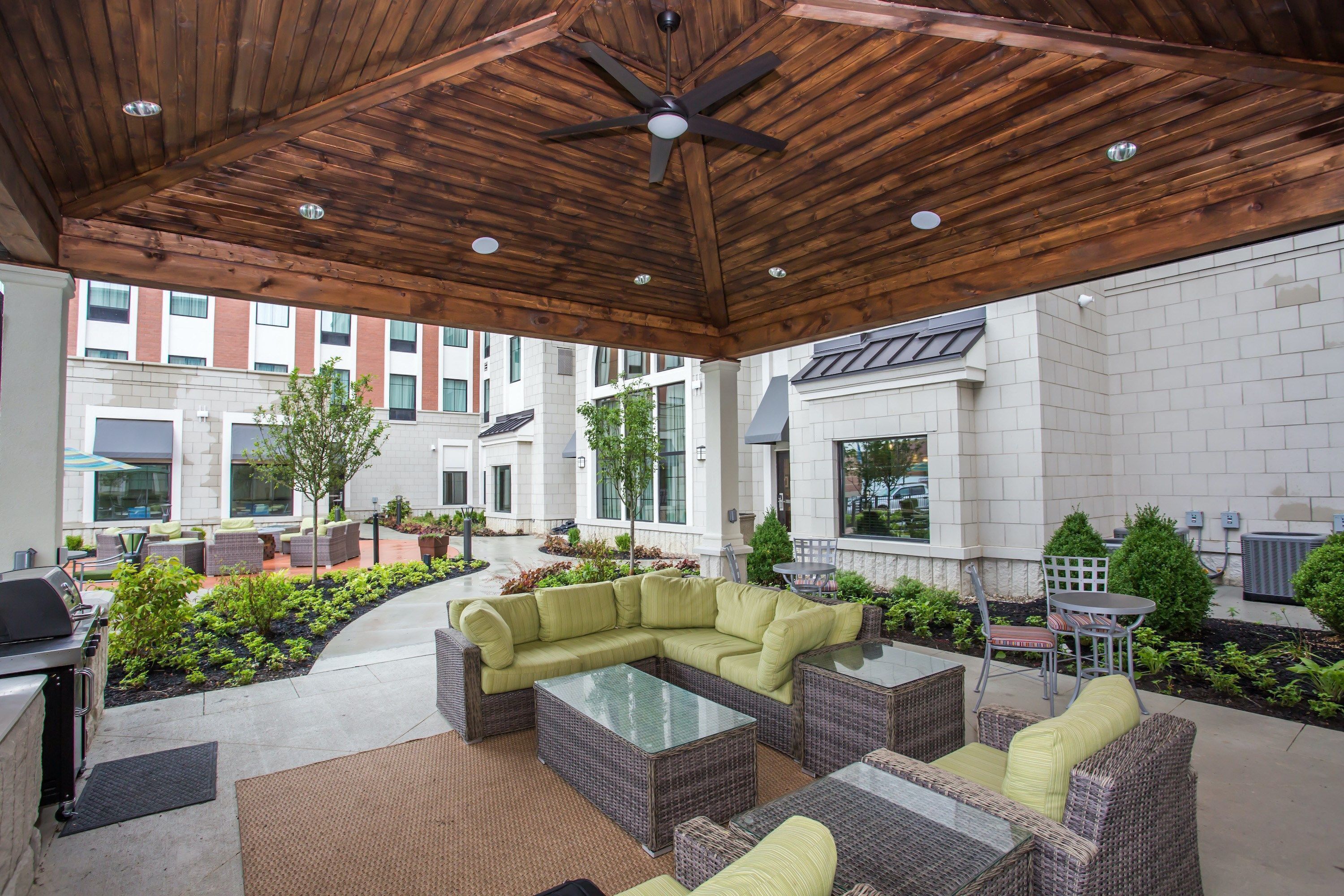 An outdoor patio area with wicker furniture, a ceiling fan, and a grill.