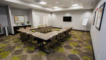 A conference room with a long table, chairs, a whiteboard, and a carpeted floor.
