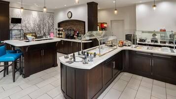 A modern kitchen with a central island, bar stools, and a built-in refrigerator.