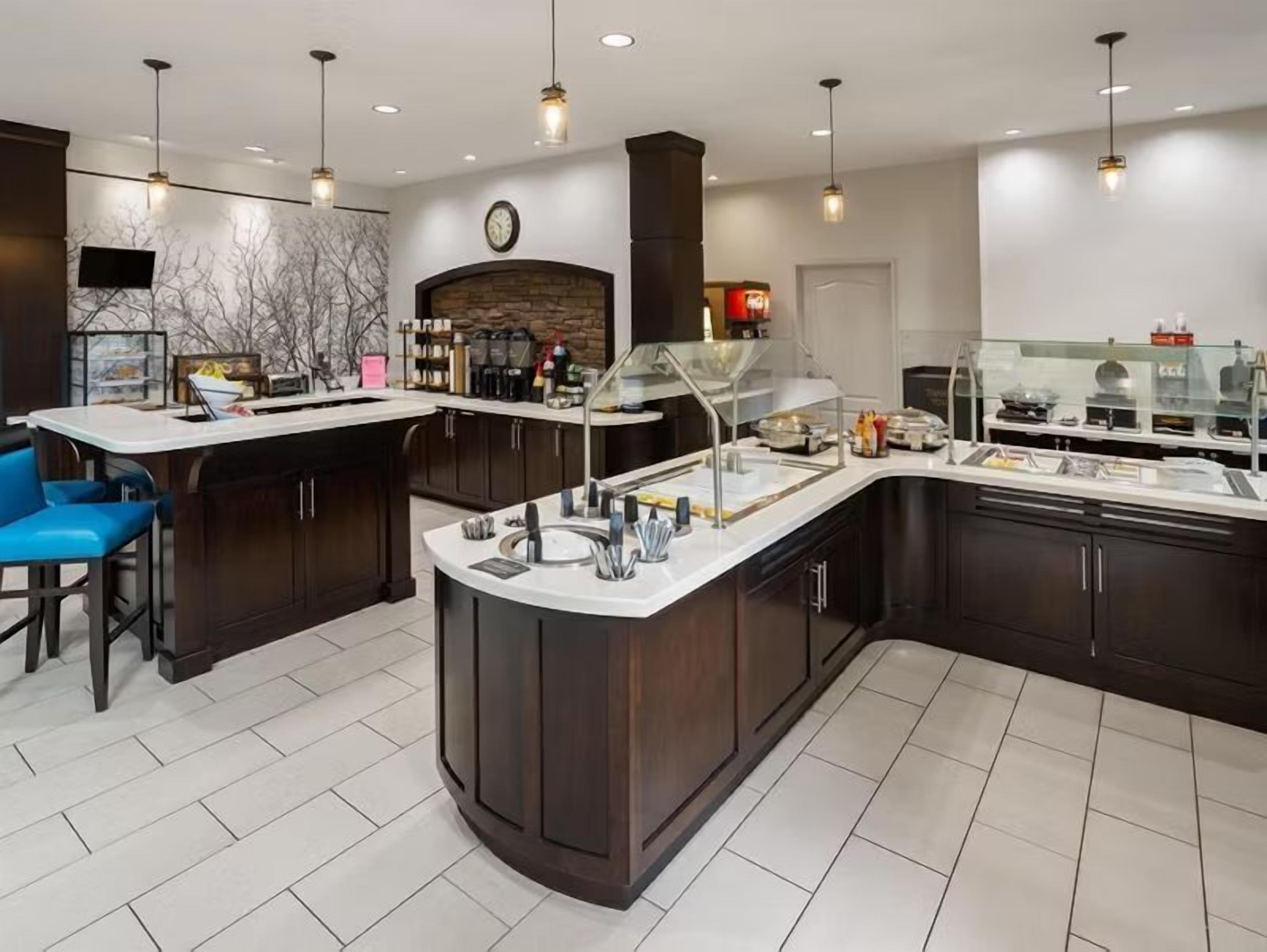 A modern kitchen with a central island, bar stools, and a built-in refrigerator.