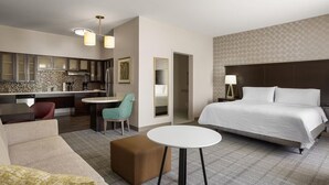 Ein Hotelzimmer mit Bett, einer Sitzecke, einem kleinen Tisch, einer Küchenzeile und einem Badezimmer.