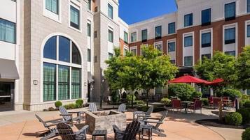 A courtyard with outdoor seating, a fire pit, and a building with multiple windows and balconies.