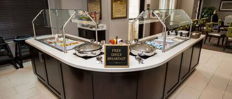 A breakfast station with a sign indicating free daily breakfast.