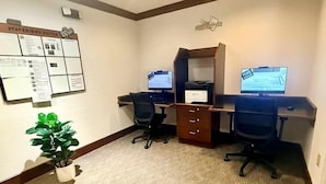 Une chambre d’hôtel équipée de deux bureaux, d’une plante en pot et d’un panneau d ’affichage contenant des informations.
