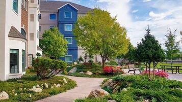 A residential building with a landscaped garden, a pathway, and a bench.
