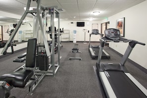 A gym with treadmills, weight machines, and benches.