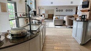A hotel lobby with a buffet area, a seating area, and a kitchen counter. - Great Falls Studio Suite | Free Breakfast! (Great Falls)