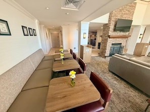 A modern interior with a long dining table, cushioned seating, a stone accent wall, and a flat-screen TV.