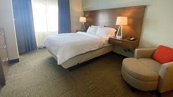 A hotel room with a bed, two bedside lamps, a chair, and a nightstand with a phone.