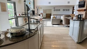 Een hotel lobby met een buffetgedeelte, een zithoek en een keukentrap.