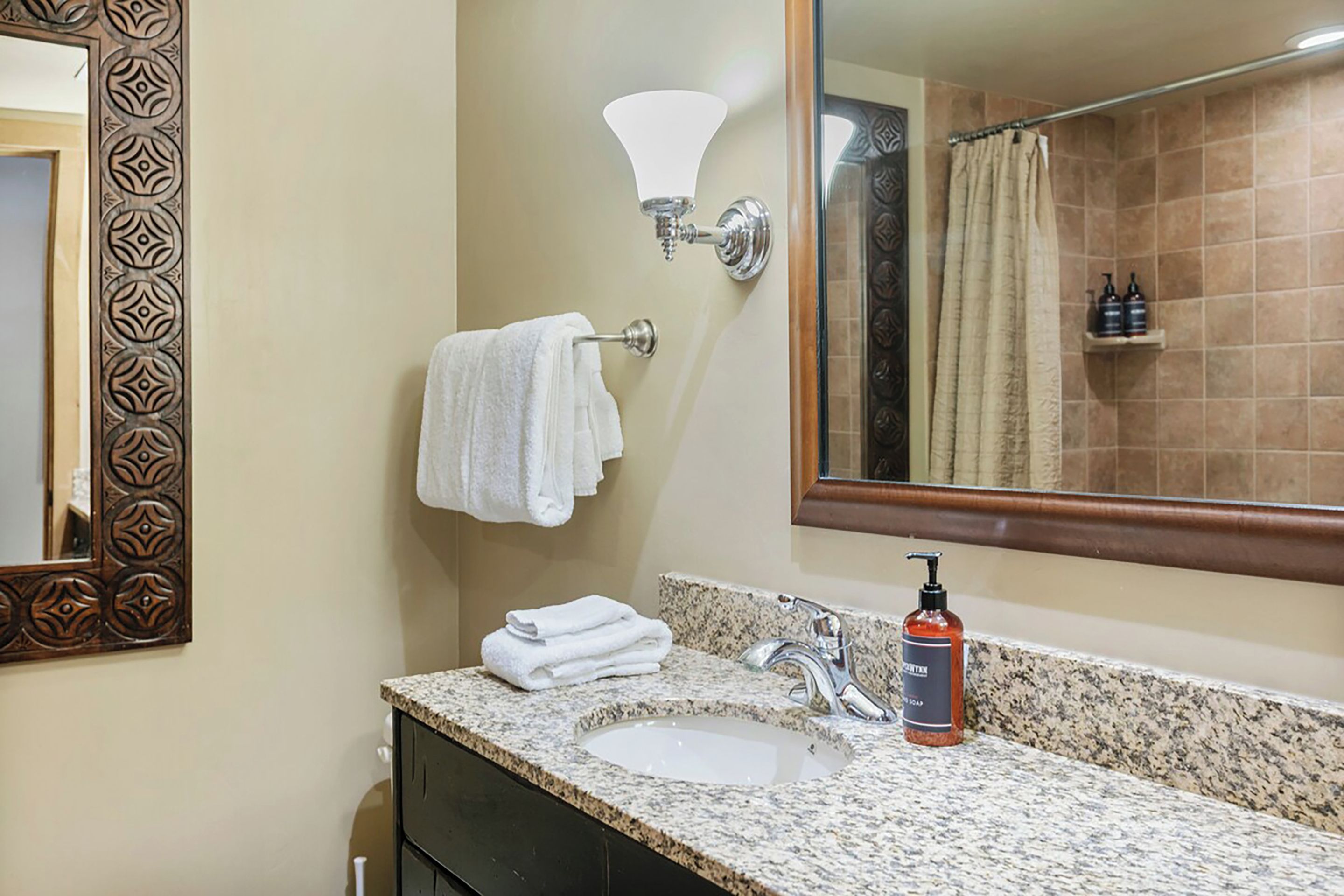 A bathroom with a sink, mirror, towel rack, and shower curtain.