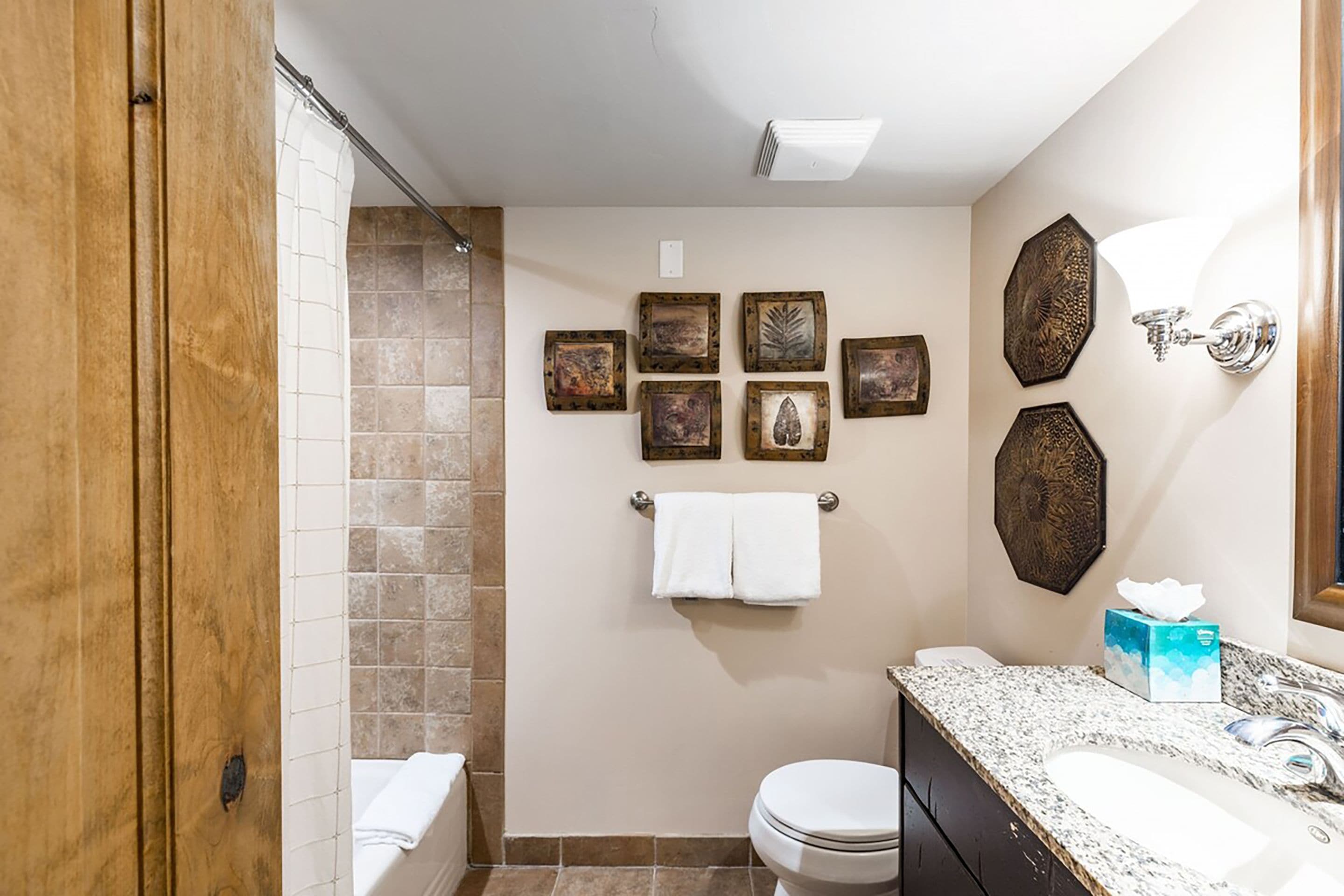 A bathroom with a shower, toilet, sink, and towel rack.