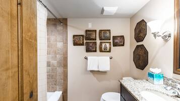 A bathroom with a shower, toilet, sink, and towel rack.