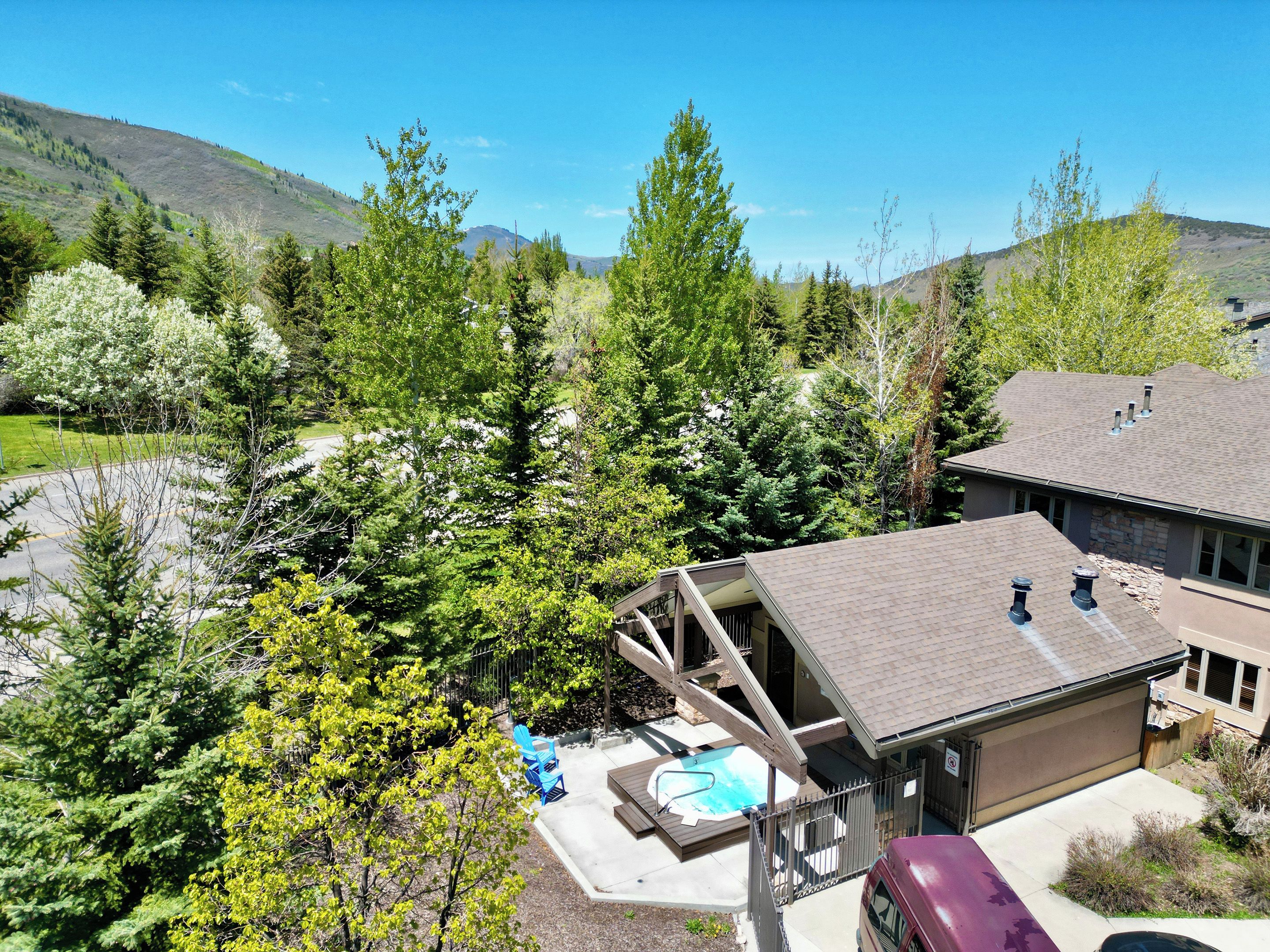 A residential property with a swimming pool, a covered patio, and a view of a mountainous landscape.
