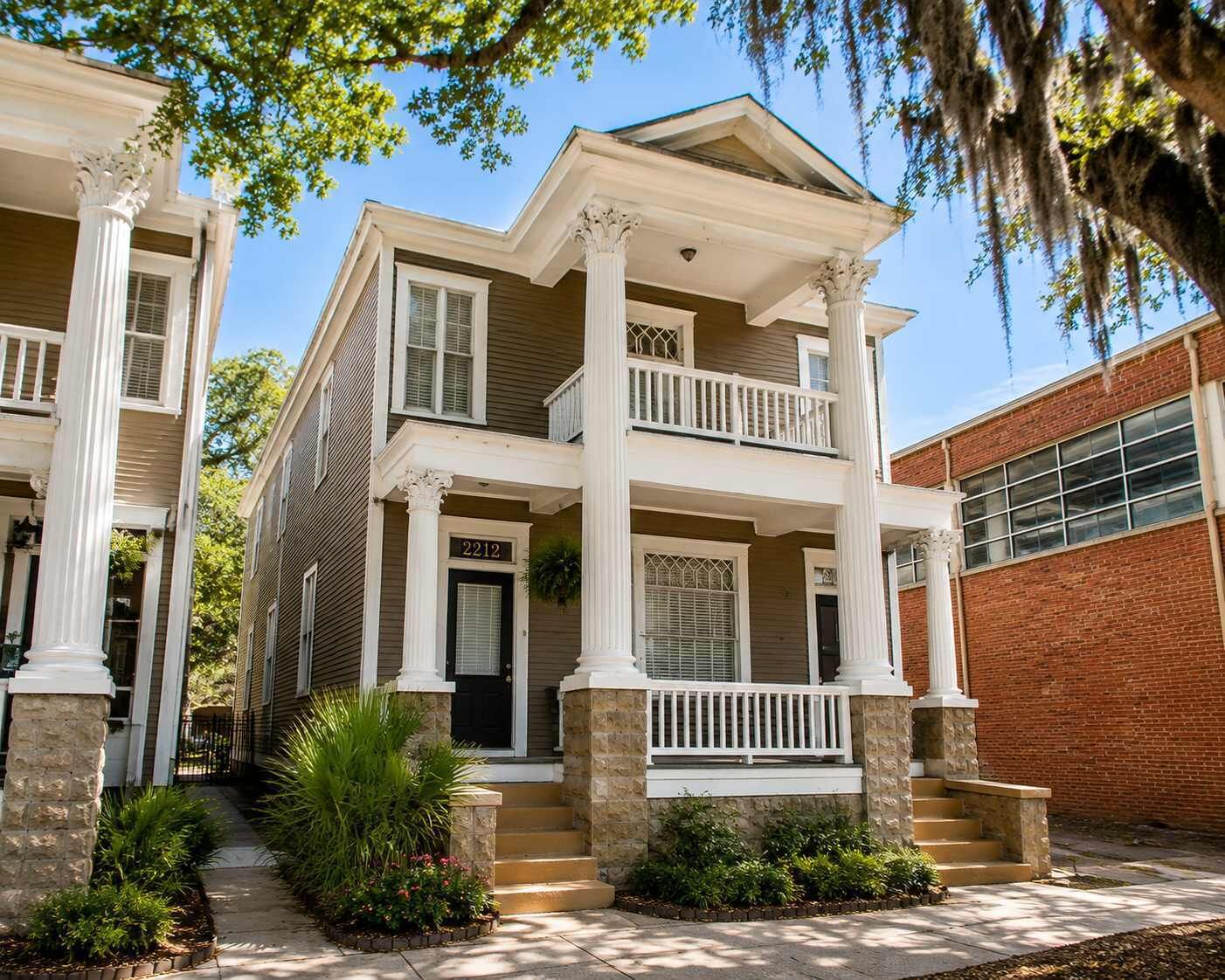 A two-story house with a front porch, columns, and a brick garage.